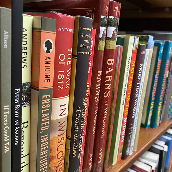 Close-up view of books lined on a shelf, beginning with If Trees Could Talk by Allison, followed by other titles placed neatly beside it.