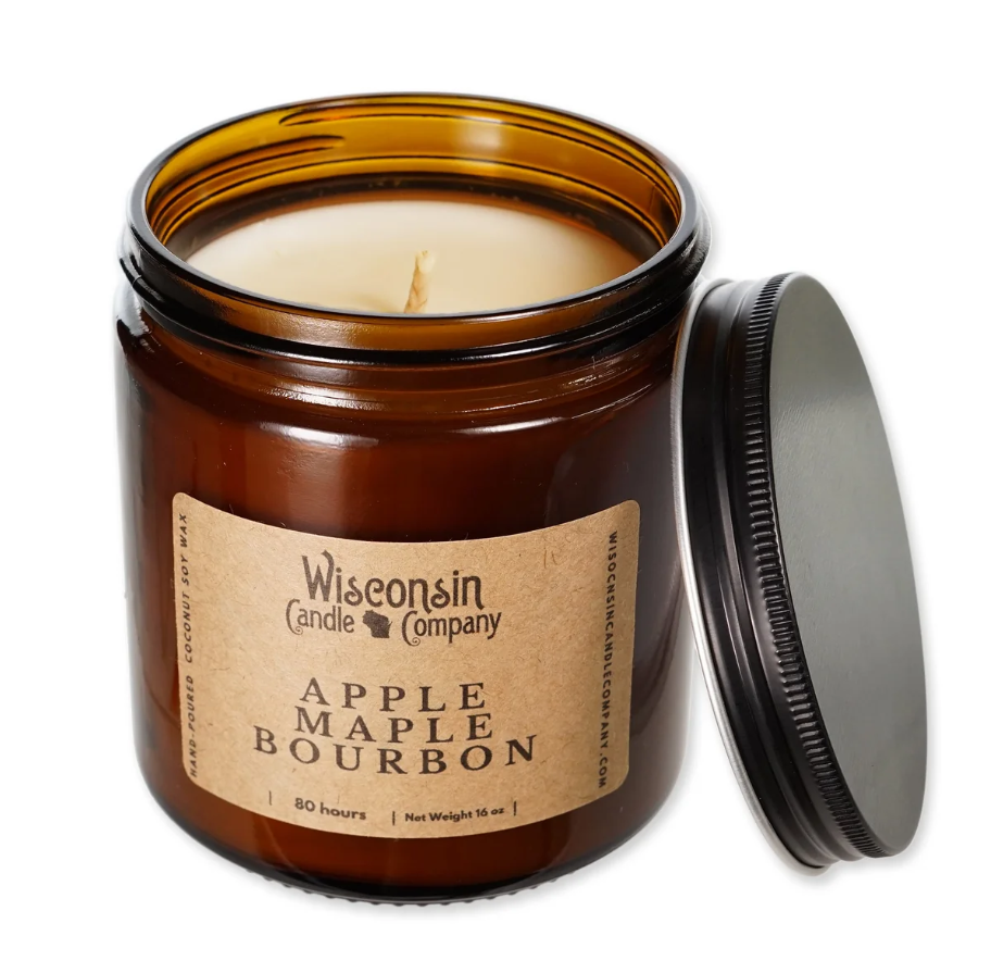 A brown glass jar with a tan label reading apple maple bourbon by Wisconsin Candle Company holds a candle