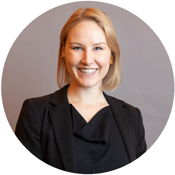 Headshot of Amanda Schultz, she has chin length blond hair and a big smile, she's wearing a chic black suit