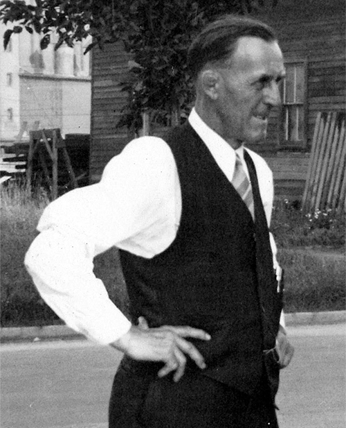Photo Credit: Circus World Museum Billy Schultz wears a black and white suit with no jacket. His hands are on his hips and he squints with a slight grimace at something off camera. He's facing profile and to the right.