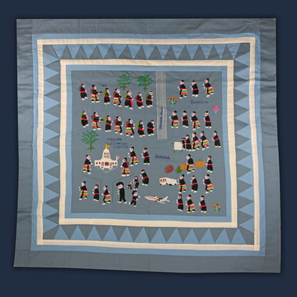 WHS MUSEUM 2017.32.2 Hand stitched journey quilt with a grey and periwinkley triangle border and straight borders. The interior depicts many brightly colored figures depicting the Secret War in Laos and the Hmong escape across the Mekong River and journeying to the U.S.A., made by Ge Yang.