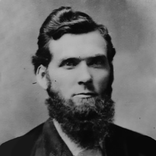 Reverend John W. Carhart, ca. 1880, looks at the camera darkly in this formal studio portrait. His beard is full, and his hair is coiffed longer on top short on the sides. His eyes are overcast but there is a slight smile on his lips.