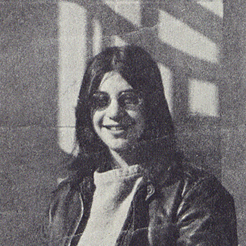 Judy Greenspan smiles happily at the camera in this outdoor photograph, wearing a leather jacket and a cowl neck like sweater. She used this photo in her campaign for School board.