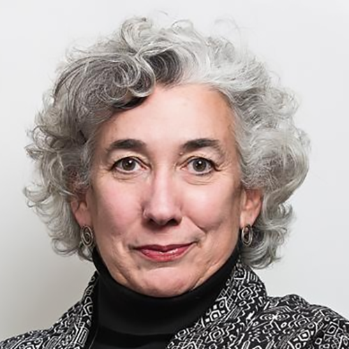 A formal portrait of Lucia Nunez, her curly hair tousled and slightly two toned, she wears a black turtle neck and a gray sweater jacket.