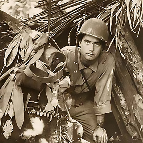 Robert Doyle emerges from a captured Japanese pillbox at Buna, New Guinea, (present day Papua New Guinea). The pillbox is built of dirt, logs and foliage.