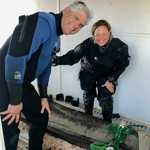 Two Wisconsin historical Society staff, a man and woman, smile for the camera after putting the canoe in the transport vehicle.