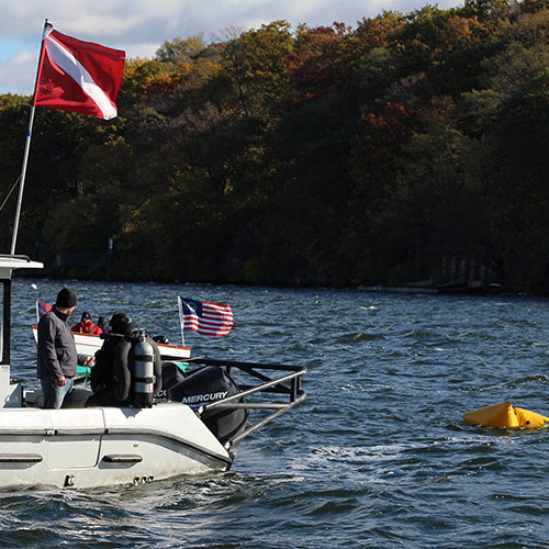 Staff members on the boat watch the divers as they move through the water.