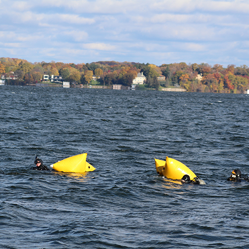 Divers using yellow floating devices to lift the boat begin swimming to the dive spot.