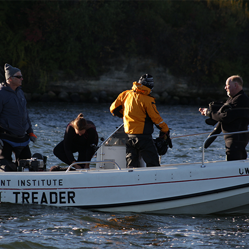 a group prepare to dive for the canoe from a boat in Lake Mendota