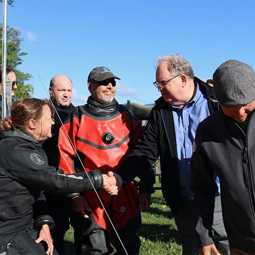  the woman who noticed the historic canoe in Lake Mendota, shakes Christian Overland's hand.