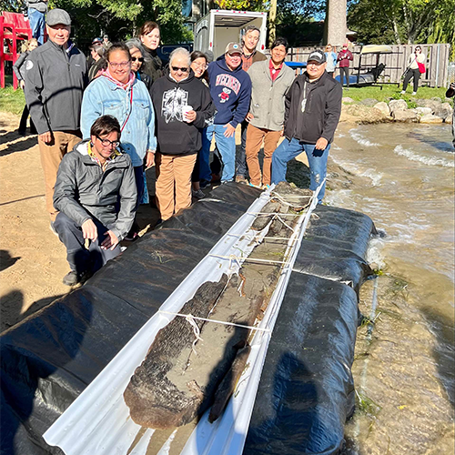Ho-Chunk and Bad River Ojibwe Nation members pose with the historic canoe of their ancestors.