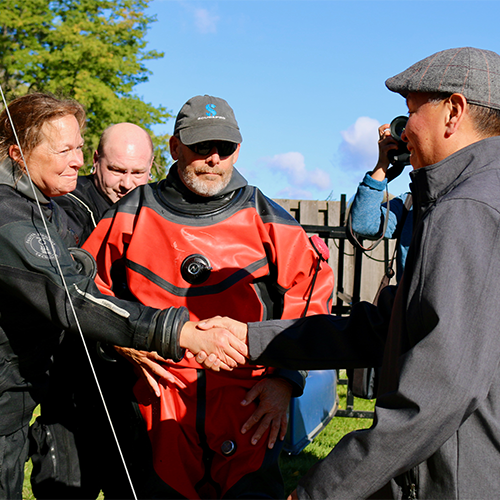 Tamara Thomsen, the woman who noticed the historic canoe in Lake Mendota, shakes Marlon WhiteEagle's hand.