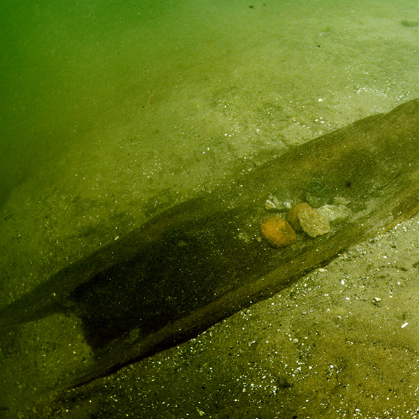 an underwater shot of an ancient dugout canoe.