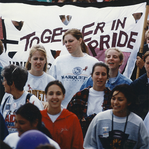 Image from the UW-Milwaukee collection featuring the AIDS Walk Wisconsin: Walkers standing in front of a banner that reads 'Together in Pride'
