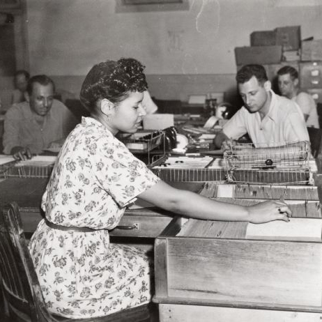 A woman at International Harvester's Tractor Works looks through a filing cabinet or a card catalog