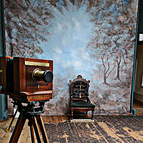 An old fashioned camera is set up facing a dramatic photo backdrop