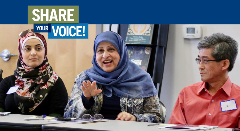 Two hijabi women talk on a panel while an older asian american man listens.