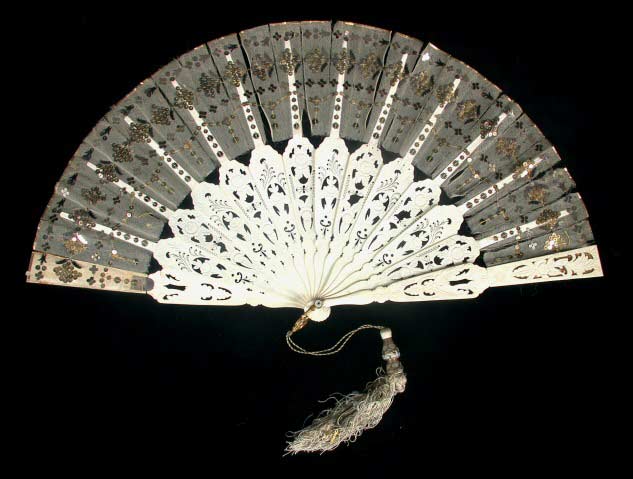 Ivory fan with carved ivory sticks, silk panels, and gold sequins applied in diamond and T shapes.