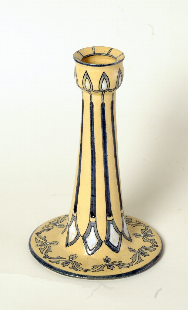 Art pottery candleholder, candlestick, stoneware, yellow, blue and white stylized candle with flame design, blue festoons at base.