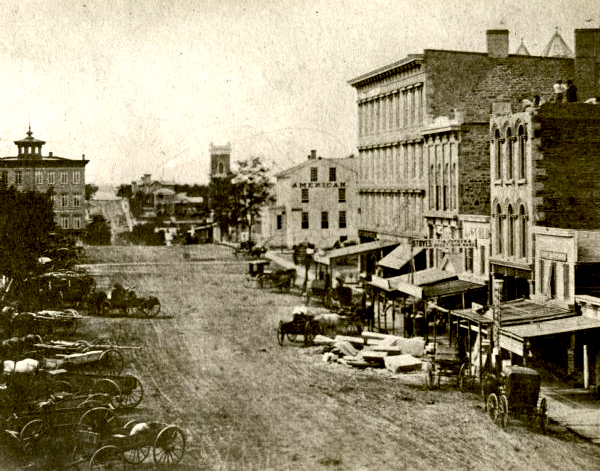Elevated view of Pickney Street looking northwest. Wagons and wooden carriages are visible parked next to the unpaved street.